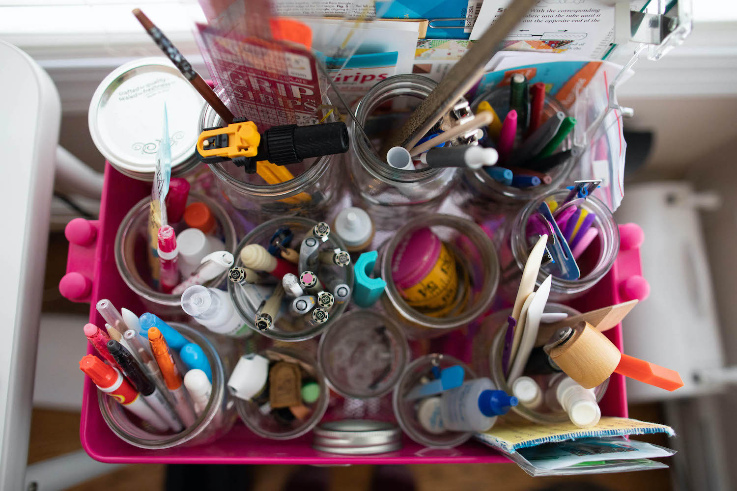 glass jars full of a variety of art supplies as seen from overhead
